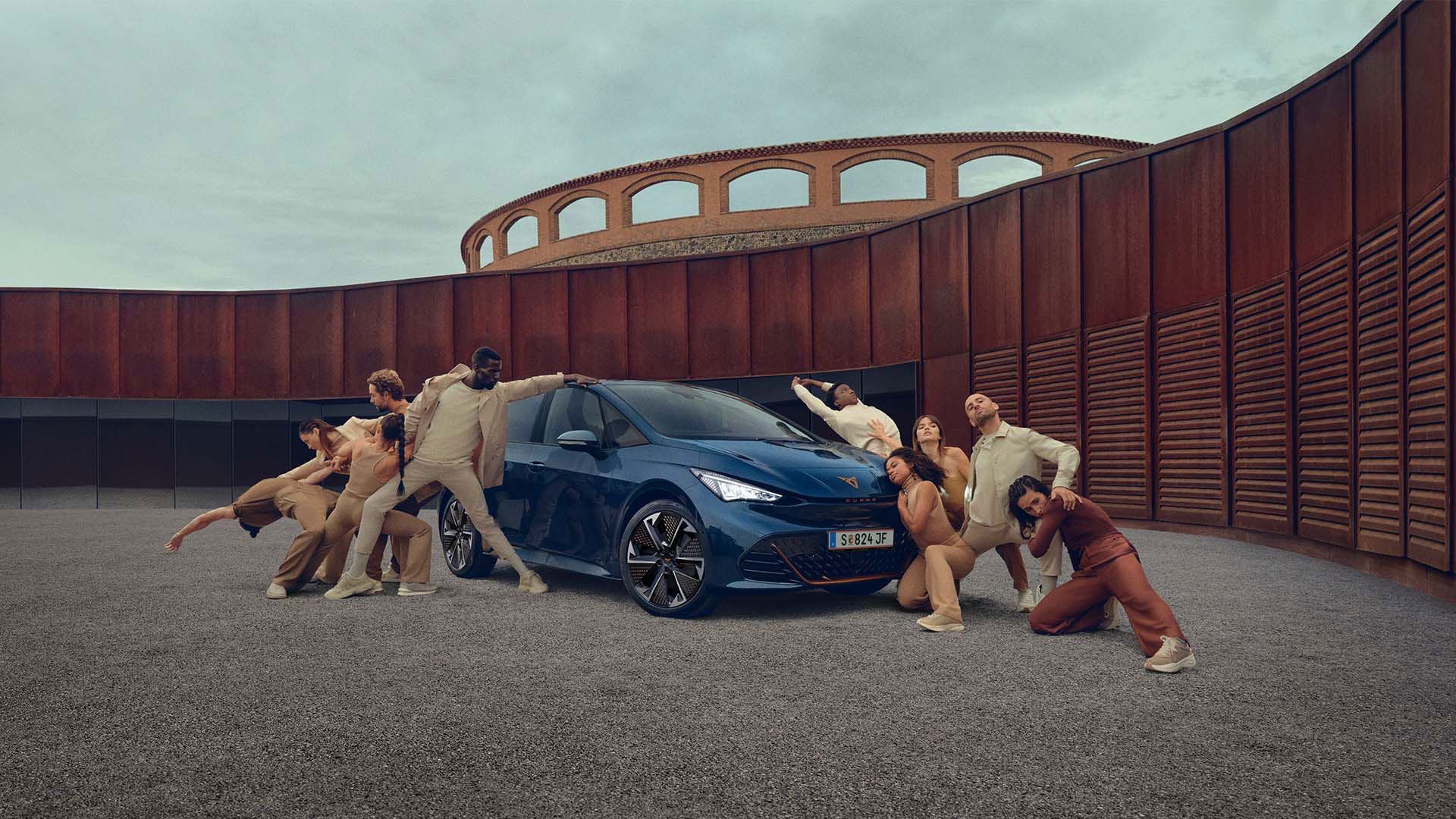 Ein blauer CUPRA Born steht auf einem Platz, mehrere Personen befinden sich links und rechts neben dem Fahrzeug.