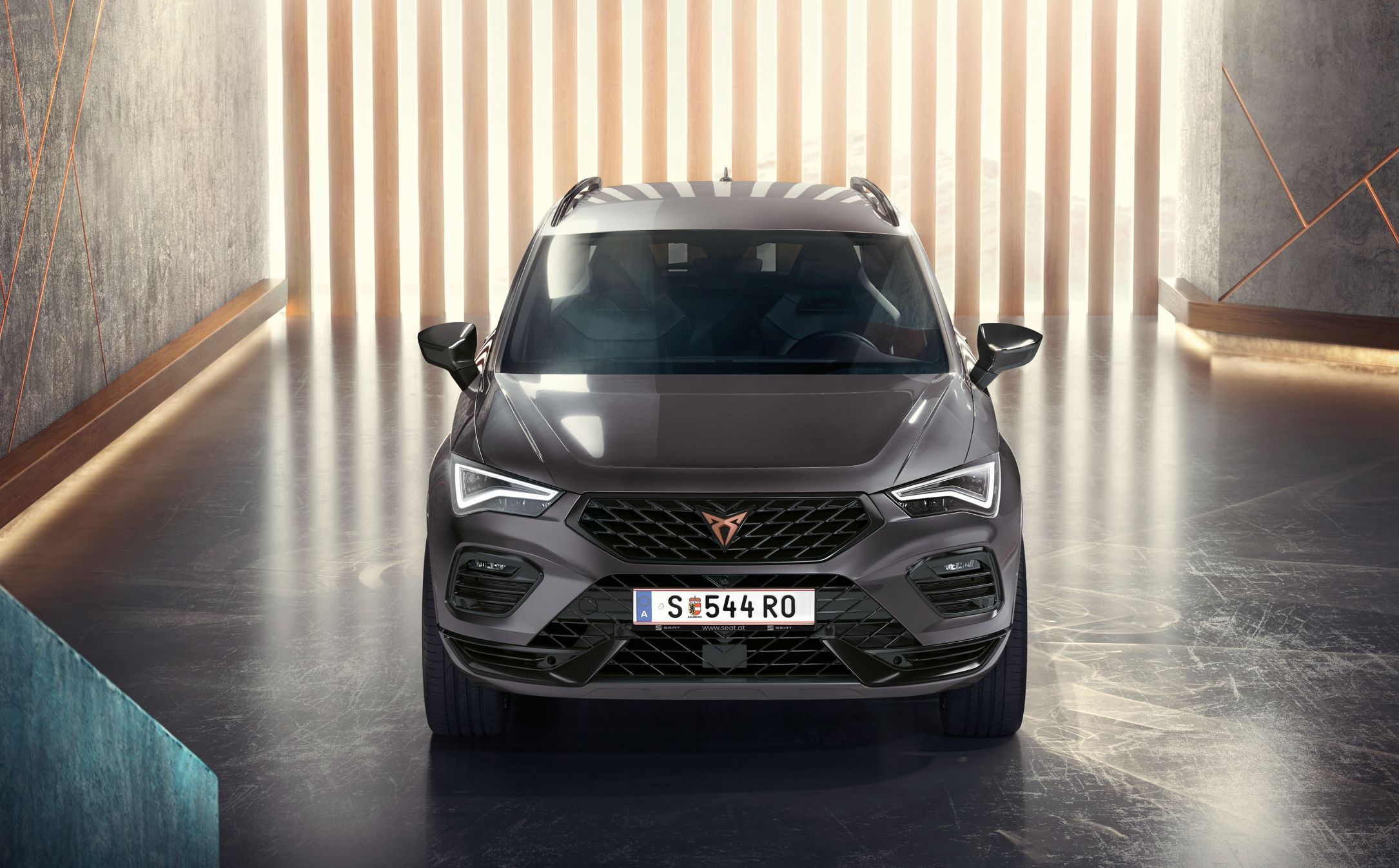 Frontansicht des CUPRA Ateca, ein grauer SUV in einer modernen, beleuchteten Umgebung. Das Bild hebt den markanten Frontgrill, die LED-Scheinwerfer und das schlanke Design hervor.